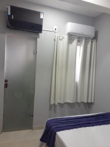 Santa Maria do SuaçuíにあるHotel Avenidaのベッド、窓、テレビが備わる客室です。