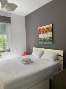a bedroom with a white bed with a painting on the wall at Green Hill Tirana Apartment in Selitë e Vogël