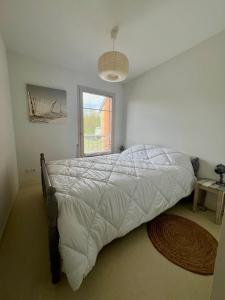 a bedroom with a bed with a white comforter and a window at Maison rêv'etang, Cayeux-sur-Mer, Baie de somme in Cayeux-sur-Mer