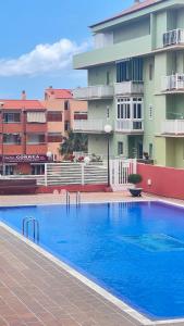 a large blue swimming pool in front of a building at Apartamento Terraza del sol con Piscina en Candelaria in Candelaria
