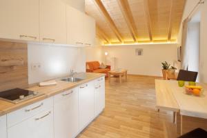 a kitchen with white cabinets and a wooden floor at Garni Unterhaslerhof in Merano