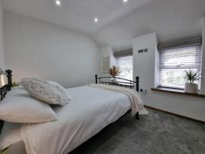 a bedroom with a bed with white sheets and pillows at Barrog Cottage in Llanfair Talhaiarn