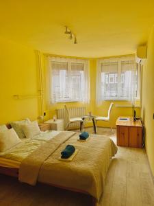 a yellow bedroom with a bed and a table and chairs at Sailor's Apartman in Siófok