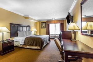 a hotel room with a large bed and a desk at Quality Inn & Suites Bell Gardens-Los Angeles in Bell Gardens