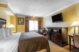 a hotel room with a bed and a flat screen tv at Quality Inn & Suites Bell Gardens-Los Angeles in Bell Gardens