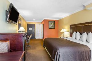 a hotel room with a bed and a flat screen tv at Quality Inn & Suites Bell Gardens-Los Angeles in Bell Gardens