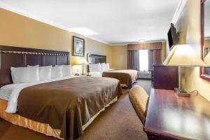 a hotel room with two beds and a desk at Quality Inn & Suites Bell Gardens-Los Angeles in Bell Gardens