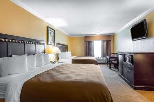 a hotel room with two beds and a flat screen tv at Quality Inn & Suites Bell Gardens-Los Angeles in Bell Gardens