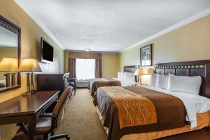 a hotel room with two beds and a desk at Quality Inn & Suites Bell Gardens-Los Angeles in Bell Gardens