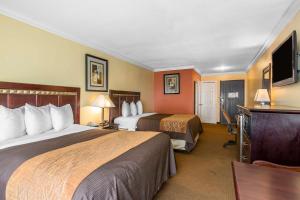 a hotel room with two beds and a flat screen tv at Quality Inn & Suites Bell Gardens-Los Angeles in Bell Gardens
