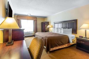 a hotel room with a bed and a table and chairs at Quality Inn & Suites Bell Gardens-Los Angeles in Bell Gardens
