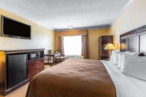 a hotel room with a large bed and a flat screen tv at Quality Inn & Suites Bell Gardens-Los Angeles in Bell Gardens