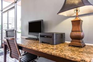 a desk with a computer and a monitor and a lamp at Quality Inn & Suites Bell Gardens-Los Angeles in Bell Gardens