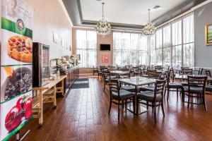 a dining room with tables and chairs and windows at Quality Inn & Suites Bell Gardens-Los Angeles in Bell Gardens