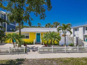 a yellow house with a blue door and palm trees at Siesta Key Island Rentals in Siesta Key