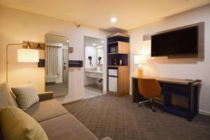 a living room with a couch and a desk with a television at Comfort Inn & Suites Moreno Valley near March Air Reserve Base in Moreno Valley