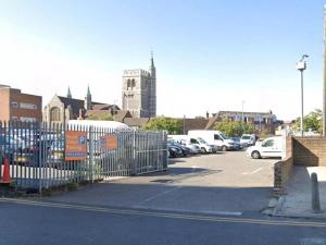 a parking lot with a gate and parked cars at Charming 2- Bedroom Apartment in Watford