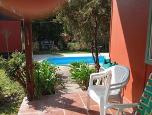 a patio with two white chairs and a swimming pool at Cabaña Los Cardenales in Gualeguaychú