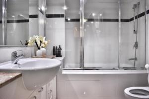 a white bathroom with a shower and a sink at Banksys Hideout London Graffiti-Style Apartment in Brisbane +24 photos