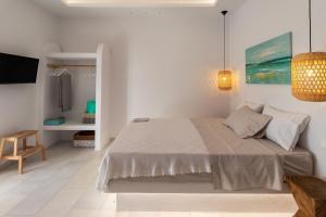 a white bedroom with a bed and a tv at Ammos Studio Pyrgaki Naxos in Agiassos