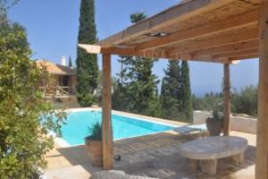 a swimming pool with a wooden pergola and a table at Storeali in Skinária