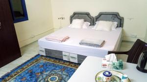 two beds in a room with two tables and chairs at SALEM House Hostel Nizwa in Nizwa