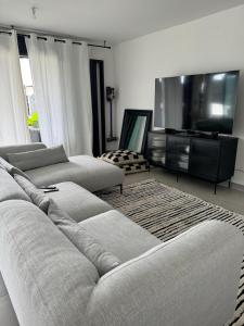 a living room with two couches and a flat screen tv at Oasis Côte Ouest 27 - Évasion chic à La Saline les Bains in La Saline les Bains