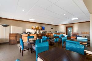a dining room with tables and blue chairs at Comfort Inn South Oceanfront in Nags Head