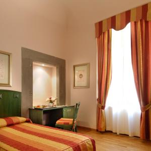 a bedroom with two beds and a desk and a window at Hotel Bologna in Pisa