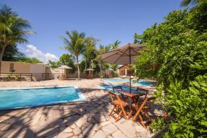 a pool with a table and chairs and an umbrella at Pousada Ponta de Mangue in Maragogi