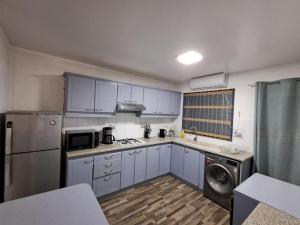 a kitchen with blue cabinets and a washer and dryer at Residence les orchidees D5 in Flic-en-Flac