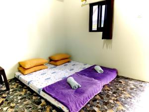 a bed in a room with purple sheets and pillows at Homestay Hidayah Sembalun in Sajang