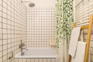 un bagno piastrellato bianco con vasca e doccia. di Near Lisbon Apartment ad Amadora Altre 21 foto