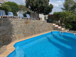 a swimming pool with chairs next to a stone wall at Casa Querencia in Frigiliana
