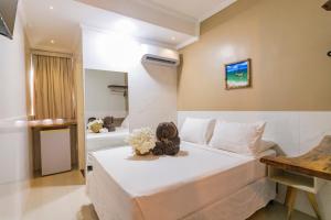 a bedroom with a large white bed with flowers on it at Pousada Ponta de Mangue in Maragogi