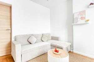 ein Wohnzimmer mit einer weißen Couch und einem Tisch in der Unterkunft L'Eden - Porte de Paris - 10 min Stade de France in Saint-Denis