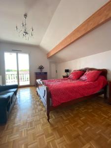 a bedroom with a bed with red sheets and a couch at Comme dans le sud in Boulot
