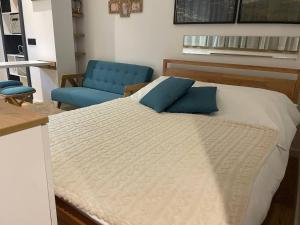 a bed with blue pillows and a blue chair at Tiny Nest - Sava Center, Belgrade in Belgrade