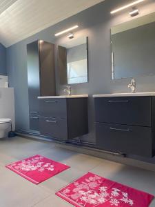 a bathroom with two sinks and two mirrors and red rugs at Comme dans le sud in Boulot +74 photos