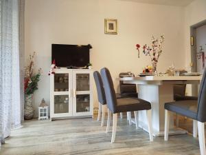 a dining room with a table and a tv on a wall at Apartmani Senka in Ika
