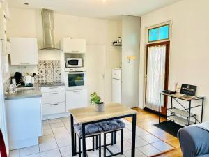 eine Küche mit weißen Geräten und einem Tisch in der Unterkunft Chez Arthur -Séjour en Sologne in La Ferté-Saint-Aubin + 6 Fotos