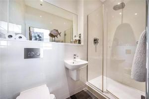 Un baño blanco con lavabo y ducha. en Exceptional Detached House with Stunning Sea Views in Bigbury on Sea Devon, en Bigbury-on-Sea