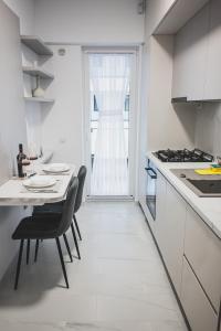 a white kitchen with a table and chairs and a window at Unirea Towers Deluxe Apartment Modern & Chic in Iaşi