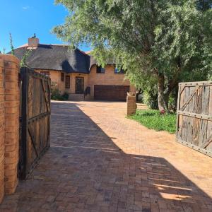 a driveway leading to a house with a wooden gate at DuckPond Lodge Cottage in Oudtshoorn