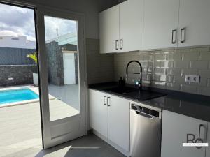 a kitchen with white cabinets and a sink and a pool at villa el rofero in Tinajo