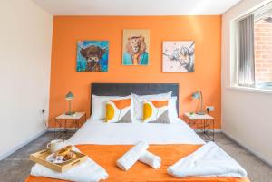 a bedroom with an orange wall with a bed and paintings at Forest View- Oasis Mural -Didsbury Zen Sleeps 10 in Manchester