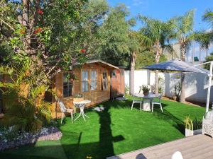 a small garden with a cabin with a table and an umbrella at הבקתה in Netanya