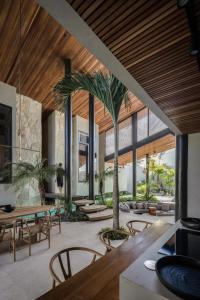 a dining room with tables and chairs and a palm tree at Can Maestro Bali by House of Winds - Lush Sanctuary near Canggu in Kerobokan +48 photos