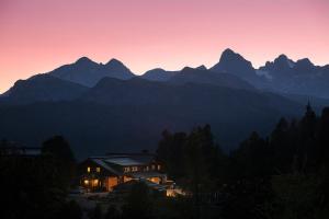 a house in front of a mountain at sunset at Steinerhaus Berggasthof in Gröbming