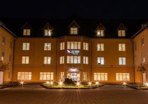 a large yellow building with lights in front of it at Vis Vitalis Hotel in Kerepes